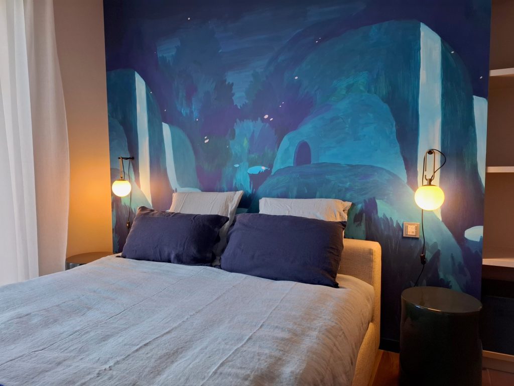 Chambre avec mur peint et lampes allumées.
